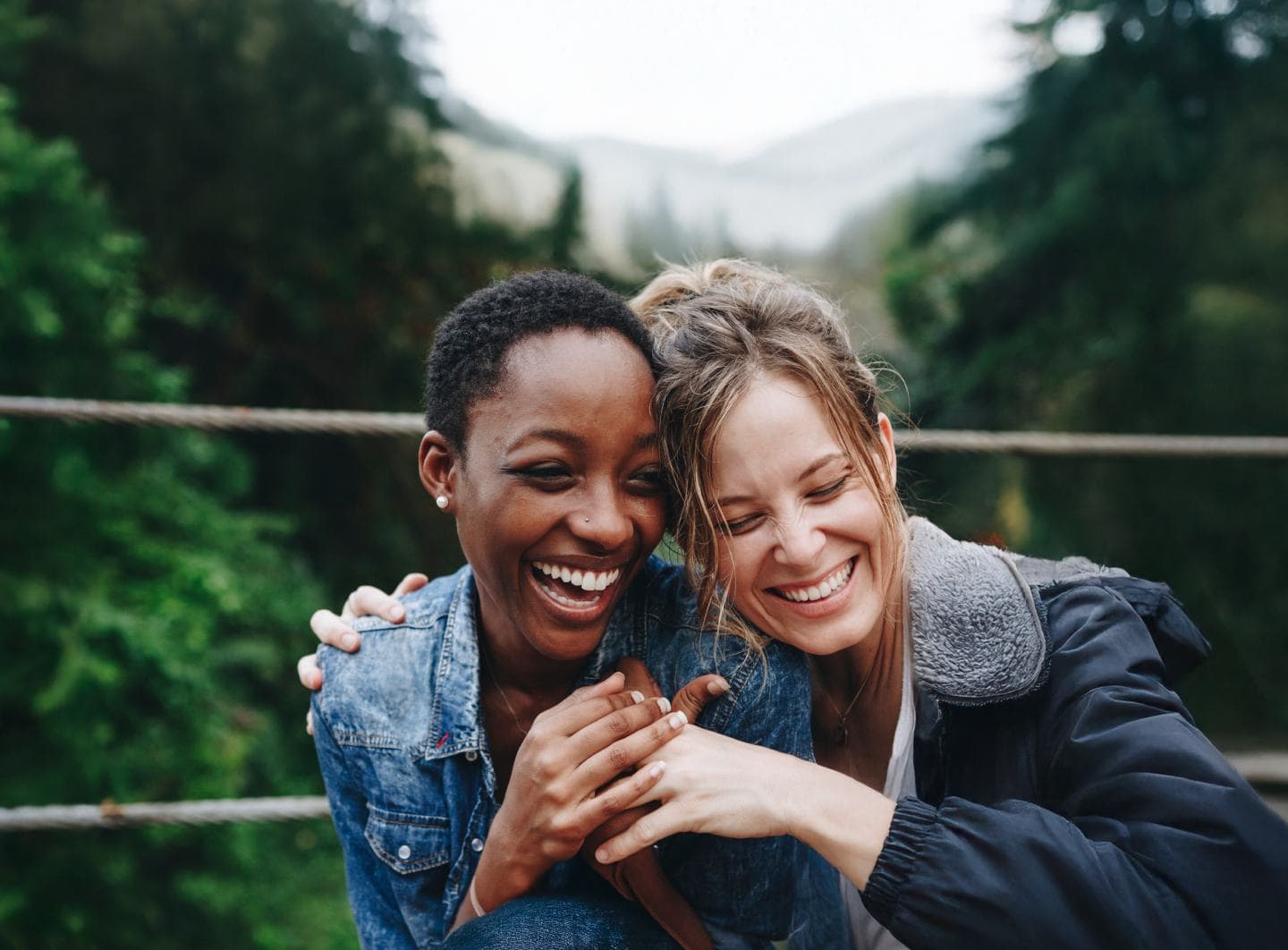 Two women smiling and enjoying time outdoors in nature.