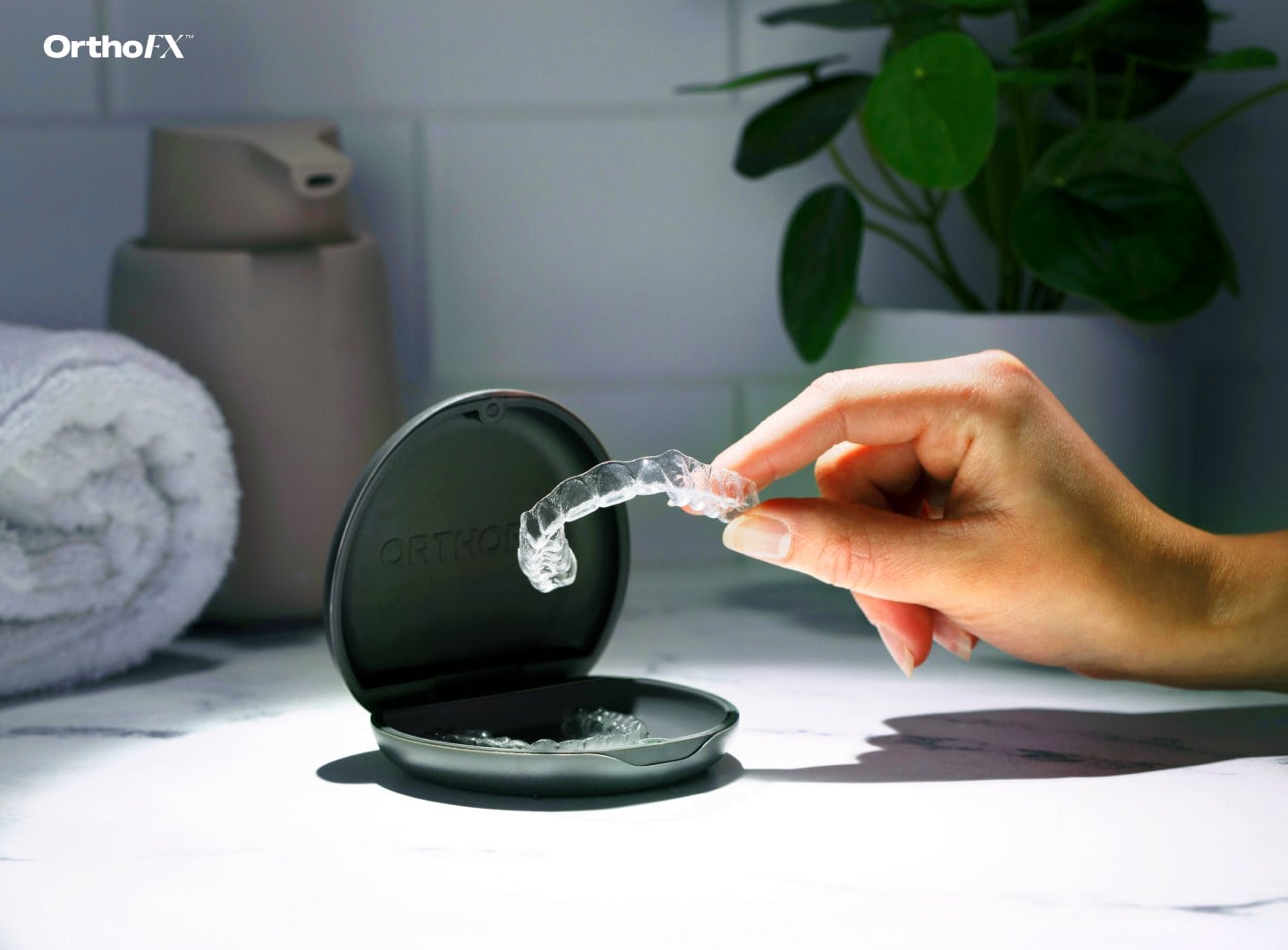 Person cleaning orthodontic retainer with cleaning tablet in a compact case.