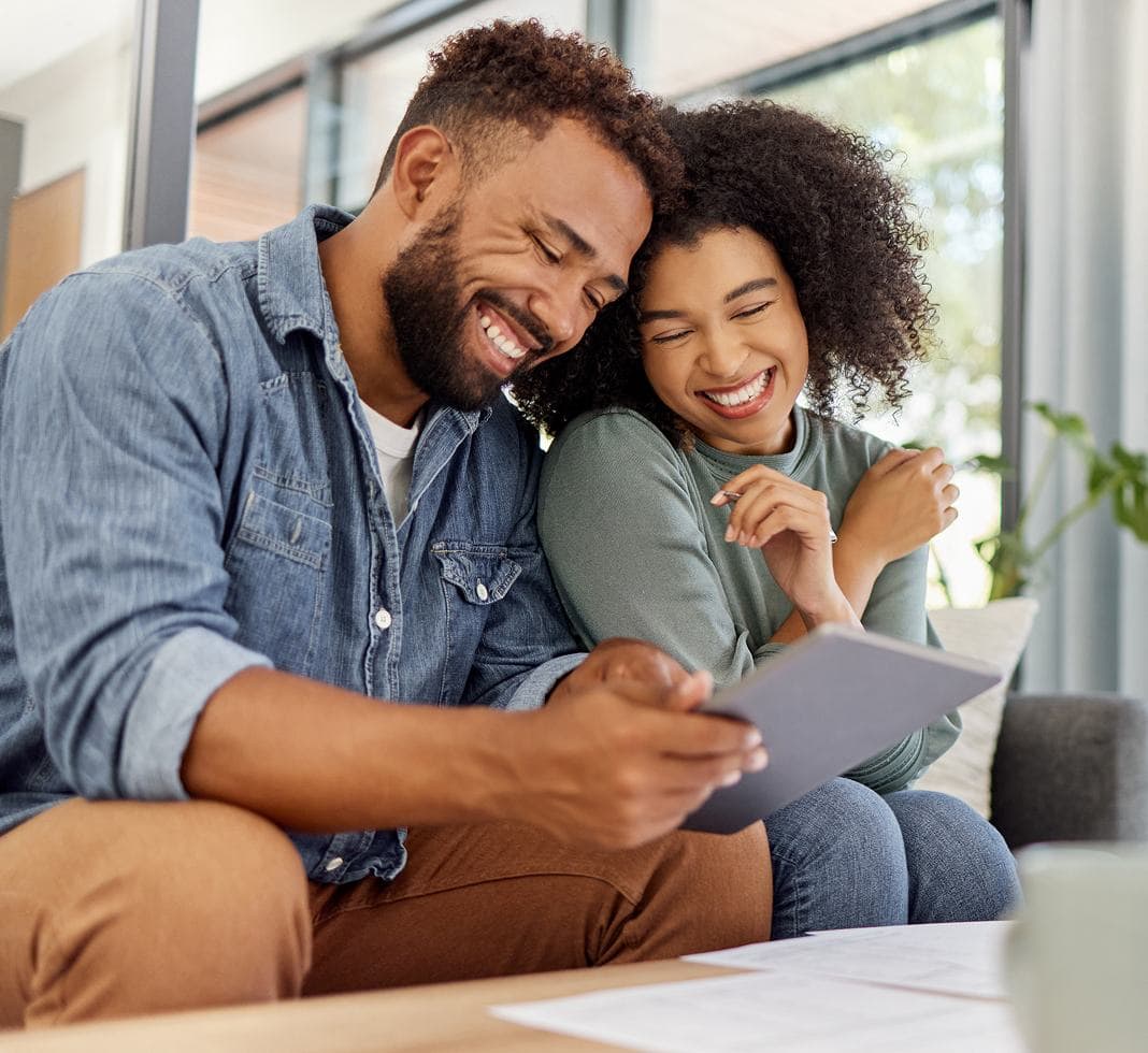 Smiling couple with dental braces looking at a tablet.