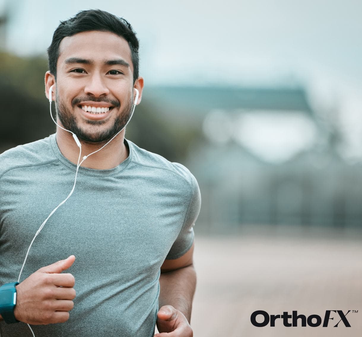 Smiling man jogging outdoors with earphones, healthy teeth, and fitness gear.