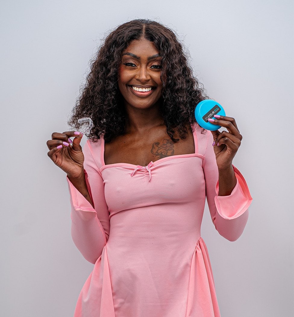 Happy woman holding a blue dental retainer case and retainer.