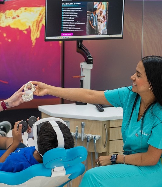 Orthodontist handing a dental model to a young patient in a modern clinic.